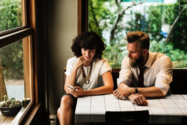 man sitting beside woman holding phone