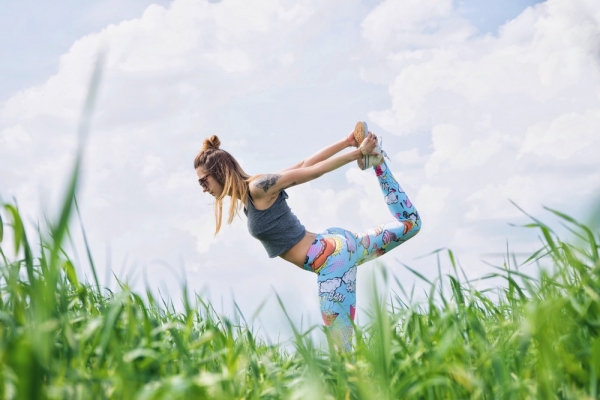 woman standing on left foot while lifting right foot upwards during daytime