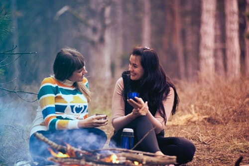 Two Women Sitting on Ground Near Bonfire