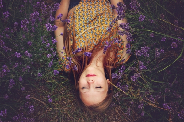 woman in yellow and teal top sleeping beside lavenders