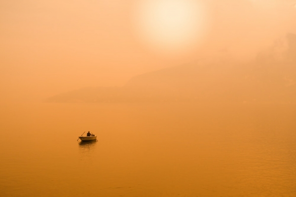 silhouette photography of person in gray sailing boat in the middle of body of water