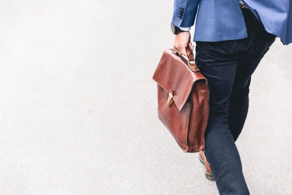 person walking holding pown leather bag